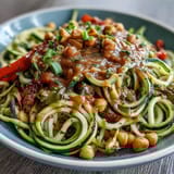 A colorful bowl of zucchini noodles stir-fried with crisp vegetables and drizzled with creamy peanut sauce. Fresh, healthy, and packed with flavor.  
