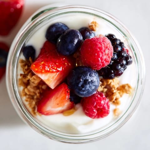 Berry Parfait in a clear glass showing vibrant red and blue berries for a healthy breakfast.