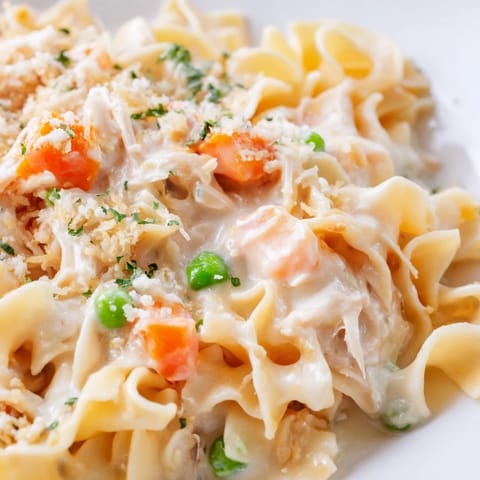 Steamy egg noodles and tender shredded chicken mingle with sweet peas and carrots in a creamy sauce in this Spring Chicken Noodle Skillet, perfect for a weeknight dinner.  