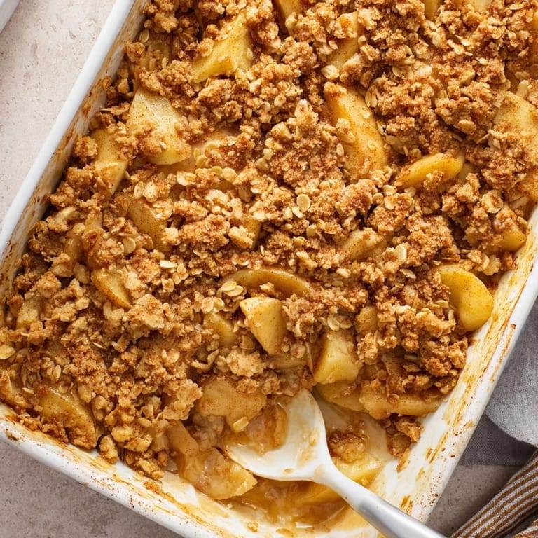 Perfectly baked Apple Crumble bubbling in a dish, featuring tender spiced apples under a crispy buttery topping.