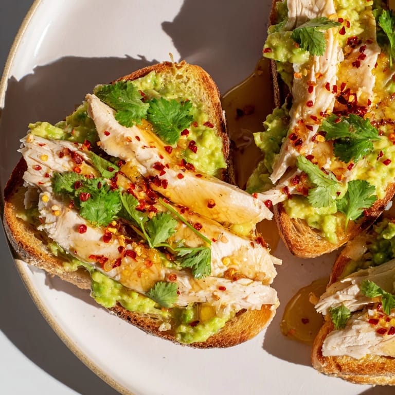 Perfectly cooked chicken and mashed avocado create a savory-sweet combo on crispy toast, ideal for a quick and flavorful brunch.