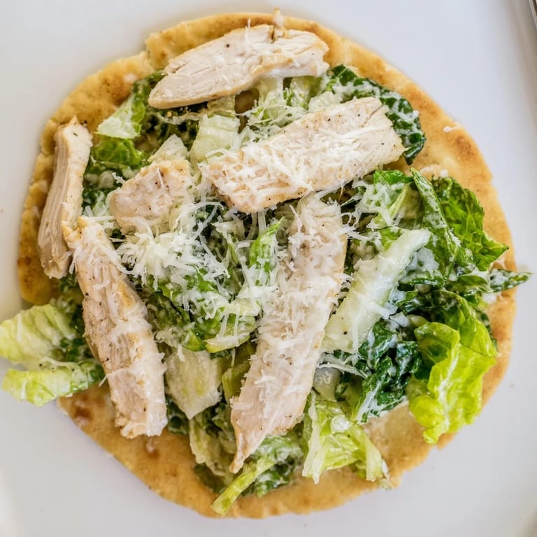 Sliced grilled chicken breast on a crispy flatbread base, garnished with cherry tomatoes and fresh parmesan.